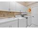 Well-lit laundry room features white cabinets, tiled backsplash, washer, dryer, and a convenient sink at 149 Albert Ln, Port Charlotte, FL 33954