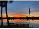 Beautiful sunset view of the water, a dock with a kayak, and a palm tree silhouetted in the dusk at 149 Albert Ln, Port Charlotte, FL 33954