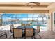 A screened patio features a dining set, brick flooring, and a lovely view of the canal and swimming pool at 15762 Aqua Cir, Port Charlotte, FL 33981