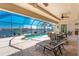 Spacious screened patio with lounge chairs, ceiling fans, a dining set, and a view of the canal and pool at 15762 Aqua Cir, Port Charlotte, FL 33981