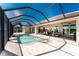 A screened pool with an attached hot tub is surrounded by brick flooring with a partial canal view at 15762 Aqua Cir, Port Charlotte, FL 33981
