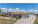 Single-story home featuring a lush lawn and a paved driveway leading to an attached garage at 18106 Petoskey Cir, Port Charlotte, FL 33948