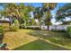 Large backyard with healthy grass, mature trees, and a white privacy fence at 2192 Hyatt Dr, Port Charlotte, FL 33948