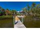 Wide view of private wooden dock leading to the house with lush tropical landscaping at 24139 Jolly Roger Blvd, Punta Gorda, FL 33955