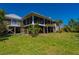 Rear exterior view featuring a screened patio, spiral staircase, and canal views, all on a lush property at 24139 Jolly Roger Blvd, Punta Gorda, FL 33955