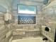 Well-designed tub and shower with gray and white tile, built in shelf, and modern shower head at 3324 Port Charlotte Blvd, Port Charlotte, FL 33952