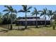 A backyard with a fenced perimeter, tall palm trees, and an enclosed patio at 384 Viedma St, Punta Gorda, FL 33983