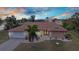 Beautiful single-story home with a well-manicured lawn, mature palms, and a two-car garage at sunset at 4473 Sweetbay St, Port Charlotte, FL 33948