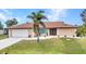 This home's appealing facade is enhanced by a verdant lawn, elegant entryway, and lush palm tree at 4473 Sweetbay St, Port Charlotte, FL 33948