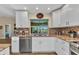 Well-lit kitchen with stainless steel dishwasher, white cabinets, and a view to the lanai at 4473 Sweetbay St, Port Charlotte, FL 33948