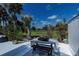 This backyard features views of the golf course with an outdoor dining set under a sunny blue sky at 5061 San Rocco Ct, Punta Gorda, FL 33950
