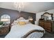 Comfortable main bedroom featuring a large bed, decorative pillows, mirrors, and a stylish chandelier at 5061 San Rocco Ct, Punta Gorda, FL 33950