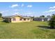Spacious backyard showcasing the rear of the cozy home under a partly cloudy sky at 558 Azalea Drive, Port Charlotte, FL 33952