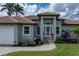 Charming home featuring a welcoming entrance, well-manicured landscaping, and a paver walkway at 571 Port Bendres Dr, Punta Gorda, FL 33950