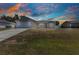 Single-story home with a neutral color scheme, attached garage, and a spacious well-maintained lawn under a dramatic sky at 6344 Hera St, Englewood, FL 34224