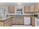 A well-lit kitchen with wood cabinets, a stainless steel sink, and white appliances at 6344 Hera St, Englewood, FL 34224