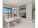 A bright dining room with a white table and a view to a pool via a large window at 8968 Artisan Way, Sarasota, FL 34240