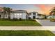 Beautiful single-Gathering home featuring a lush lawn and a paved driveway against a colorful sunset sky at 8968 Artisan Way, Sarasota, FL 34240
