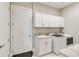 Functional laundry room with white cabinets, sink, and modern washer and dryer for convenient chores at 8968 Artisan Way, Sarasota, FL 34240