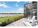 Relaxing patio with white Adirondack chairs overlooking a serene lake view and lush landscaping at 8968 Artisan Way, Sarasota, FL 34240