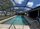 A screened-in swimming pool with brick paver surround near a waterfront canal at 931 Juno Dr, Punta Gorda, FL 33950