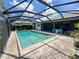 Screened-in pool area featuring brick pavers, canal view, lush landscaping and a clear blue swimming pool at 931 Juno Dr, Punta Gorda, FL 33950