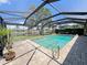 Screened-in pool area featuring brick pavers, canal view, lush landscaping and a clear blue swimming pool at 931 Juno Dr, Punta Gorda, FL 33950