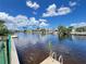 Calm waterfront view with a dock, featuring neighboring homes with lush landscaping and boats docked in the canal at 931 Juno Dr, Punta Gorda, FL 33950