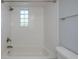 Close up of the tub/shower in a bathroom with a white tiled surround and a glass block window at 1051 Forrest Nelson Blvd # 104, Port Charlotte, FL 33952
