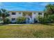 Inviting two-story condo building featuring lovely landscaping and a well-maintained lawn under a clear blue sky at 1051 Forrest Nelson Blvd # 104, Port Charlotte, FL 33952