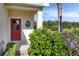Charming front entrance with red door, round window, and lush landscaping at 1085 Jonah Dr, North Port, FL 34289
