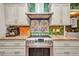 Close up of oven and stovetop area, with decorative tile backsplash and stainless steel hood at 1357 Le Pera Rd, Englewood, FL 34223