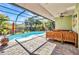 A screened-in pool area with palm trees, outdoor seating, and a refreshing swimming pool at 1357 Le Pera Rd, Englewood, FL 34223