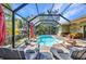 Seating area on a screened-in brick patio next to a pool with a tropical landscape at 1357 Le Pera Rd, Englewood, FL 34223
