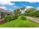 A well-maintained backyard with green grass, a white fence, and a covered patio area at 1814 Pinyon Pine Dr, Sarasota, FL 34240