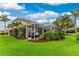 A well-maintained backyard with green grass, a covered patio area, and palm trees at 1814 Pinyon Pine Dr, Sarasota, FL 34240