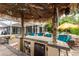 Outdoor tiki bar featuring a mini refrigerator, storage, stone countertop and seating for four at 1814 Pinyon Pine Dr, Sarasota, FL 34240