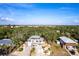 Aerial front view of a home in a neighborhood among lush trees and clear blue skies at 1851 Scenic Dr, Venice, FL 34293