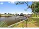 View of boat dock with boat lift on canal with lush green landscaping and blue sky at 21169 Edgewater Dr, Port Charlotte, FL 33952