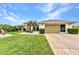 Well-maintained home with brick driveway, lush lawn, and landscaping, showcasing excellent curb appeal at 23104 Turnbull Ave, Port Charlotte, FL 33954