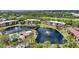 Aerial view of condo community with pond, fountains, clubhouse, and lush landscaping at 23465 Harborview Rd # 925, Punta Gorda, FL 33980