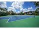 Community tennis courts surrounded by mature trees and a view of the multi-story condo building at 23465 Harborview Rd # 925, Punta Gorda, FL 33980