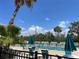 A great view of the community pool with umbrellas and lounge chairs, and lush palm tree landscaping at 25188 Marion Ave # F307, Punta Gorda, FL 33950