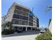 Low-angle view of a condo building with balconies and covered parking, near the beach and palm trees at 25188 Marion Ave # F307, Punta Gorda, FL 33950
