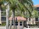 A community guard house set amongst lush trees and landscaping featuring a clay tile roof at 25188 Marion Ave # F307, Punta Gorda, FL 33950