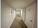 Long hallway with carpet, multiple doors, artwork, and storage in neutral tones at 25188 Marion Ave # F307, Punta Gorda, FL 33950