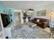 Open-concept living room with palm-themed rug, ceiling fan, and bar seating at 25188 Marion Ave # F307, Punta Gorda, FL 33950