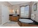 Bathroom featuring double sinks, a standalone tub, and neutral tile flooring at 48 Colony Point Dr, Punta Gorda, FL 33950