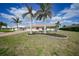 Well-maintained single-story home featuring mature palm trees, lush landscaping, and a vibrant red front door at 530 Matares Dr, Punta Gorda, FL 33950