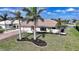 Charming single-story home featuring mature landscaping, a red front door, and a brick driveway at 530 Matares Dr, Punta Gorda, FL 33950